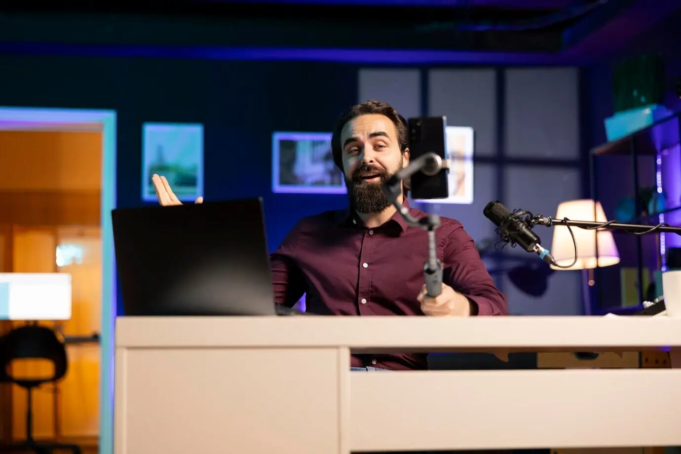 Радостный инфлюенсер в домашней студии приветствует аудиторию во время записи прямого эфира.